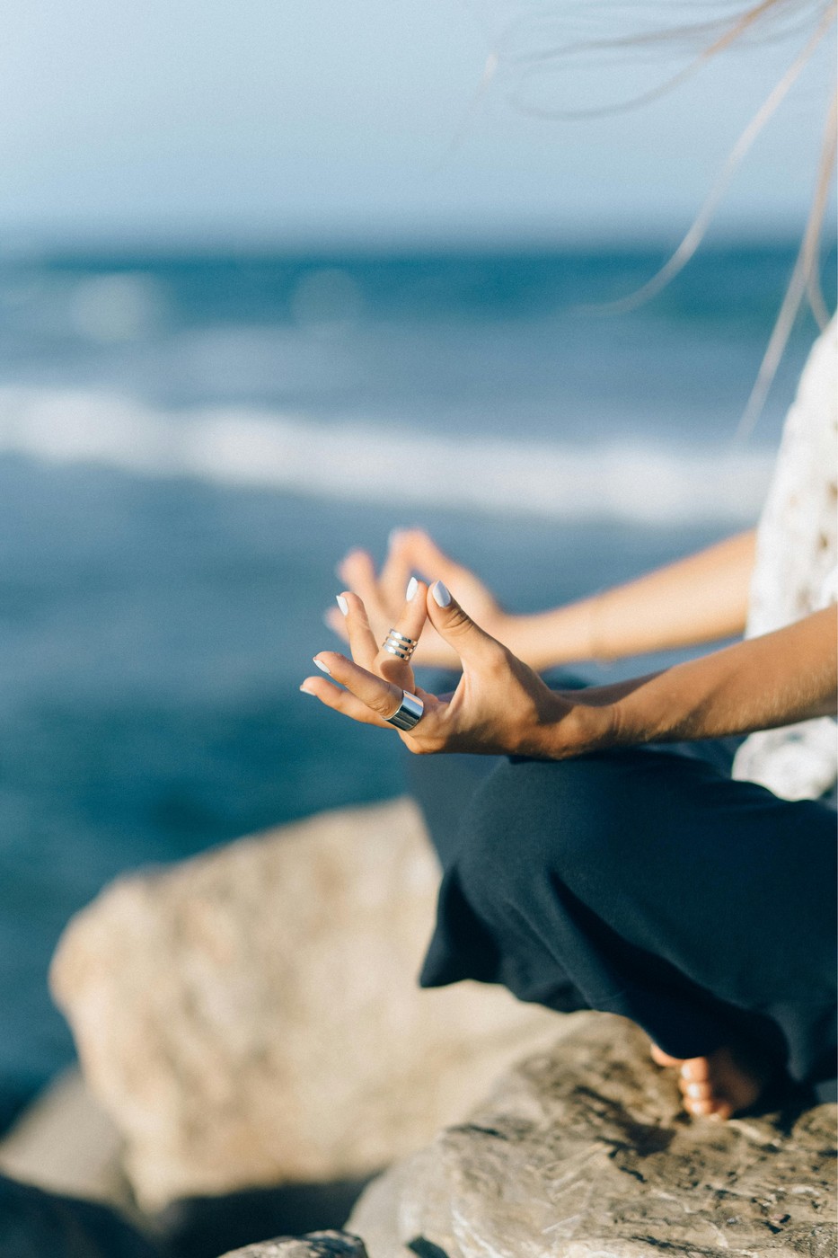 Hands resting in a mudra by the ocean